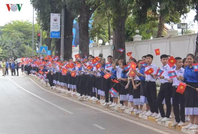 A large number of Lao people in traditional costumes standing along streets welcome the Party chief.