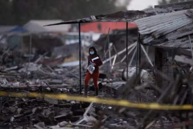 A woman walks amidst the remains of houses destroyed in an explosion at the San Pablito fireworks market outside the Mexican capital on Tuesday, in Tultepec, Mexico, December 20, 2016. REUTERS/Edgard Garrido