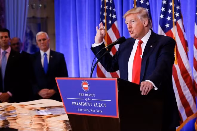 Vice President-elect Mike Pence is seen in the background as U.S. President-elect Donald Trump speaks during a press conference in Trump Tower, Manhattan, New York, U.S., January 11, 2017. REUTERS/Shannon Stapleton