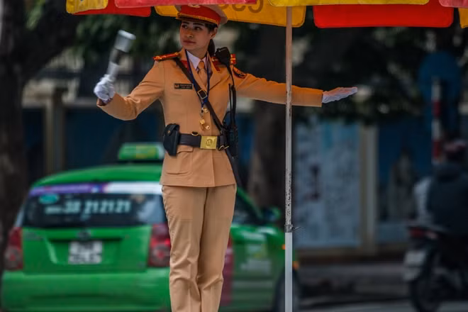 A young female police officer of Traffic Police Office 2 under the Hanoi Traffic Police Division is performing her duty at the Dien Bien Phu - Tran Phu intersection from early morning.
