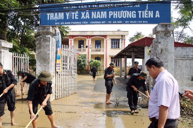 Hanoi's Mobile Police help locals clean up roads after prolonged flooding.