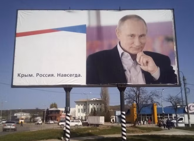 A billboard with a portrait of Russian President Vladimir Putin is displayed on a street in Kerch, Crimea, April 7, 2016. The board reads: ''Crimea. Russia. Forever.'' REUTERS/Andrew Osborn/File Photo