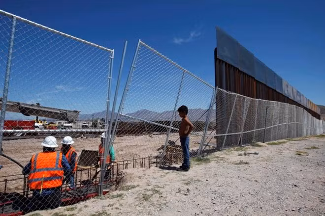 A boy looks at U.S. workers building a section of the U.S.-Mexico border wall at Sunland Park, U.S. opposite the Mexican border city of Ciudad Juarez, Mexico. REUTERS/Jose Luis Gonzalez