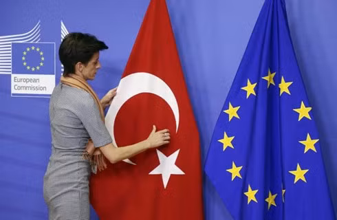A woman adjusts the Turkish flag next to the European Union flag before the arrival of Turkish Prime Minister Ahmet Davutoglu (unseen) at the EU Commission headquarters in Brussels January 15, 2015. (Photo: Reuters)