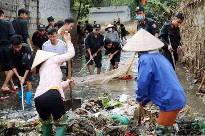 Hanoi's Mobile Police help locals clean up roads after prolonged flooding.