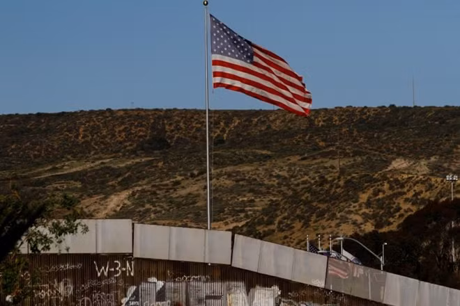 A U.S. flag is seen next to a section of the wall separating Mexico and the United States, in Tijuana, Mexico, January 28, 2017. REUTERS/Jorge Duenes