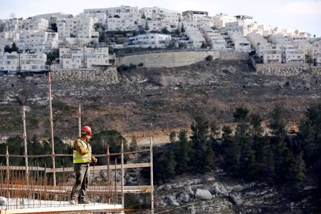 A labourer works at a construction site in the Israeli settlement of Ramot, as the Israeli settlement of Ramat Shlomo is seen in the background, in an area of the occupied West Bank that Israel annexed to Jerusalem January 22, 2017. REUTERS/Ronen Zvulun