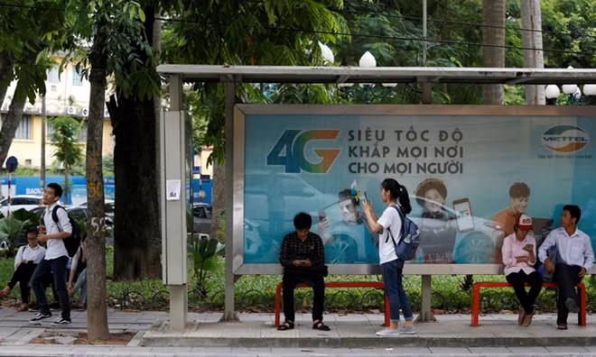 People browse the internet near an advertising billboard for 4G connection service at a bus-stop in Hanoi, August 29, 2017. Photo by Reuters/Kham