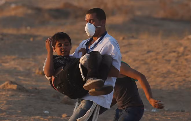 A wounded Palestinian boy is evacuted during a protest calling for lifting the Israeli blockade on Gaza and demanding the right to return to their homeland, at the Israel-Gaza border fence in the southern Gaza Strip October 12, 2018. REUTERS/Ibraheem Abu Mustafa