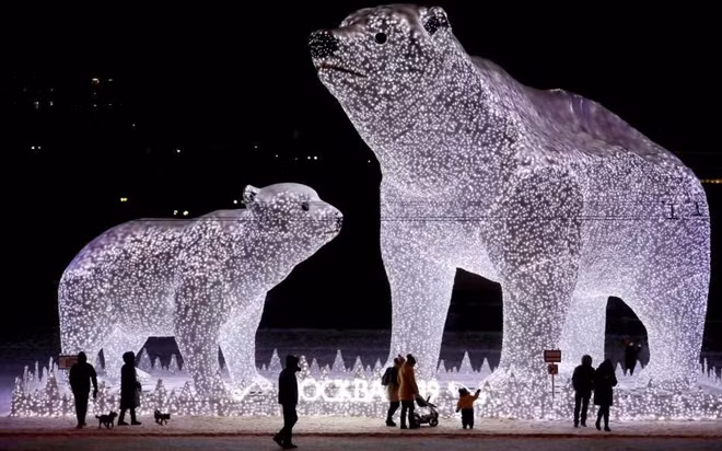 People walk near huge light sculptures of polar bears installed as part of decoration for the New Year and Christmas holidays in one of districts of Moscow, Russia, on Dec. 28.