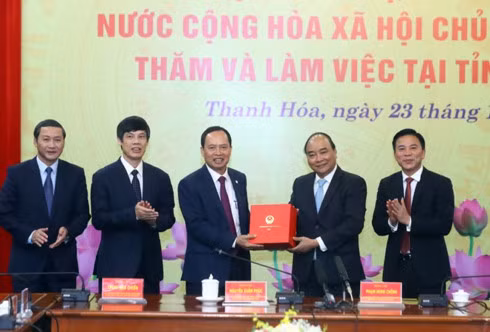 Prime Minister Nguyen Xuan Phuc (second, right) presents a gift to Thanh Hoa authorities at the working session on December 23.