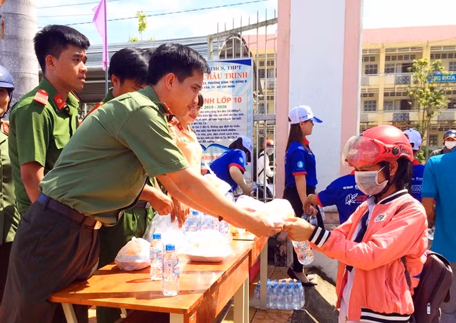 A police officer offers free water bottle to student. A police officer offers free water bottle to student.