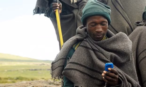 A Lesothan shepherd uses a mobile phone in Northern Drakensberg. Photograph: Richard Wareham Fotografie Afrik/Alamy