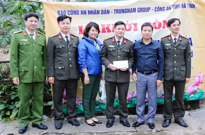 Representatives of CAND Newspaper working team and Trung Nam Group handing money to two policemen in Ha tinh
