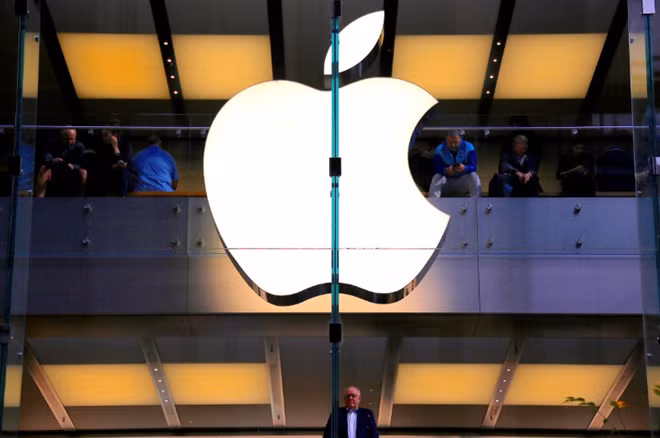 A customer stands underneath an illuminated Apple logo as he looks out the window of the Apple store located in central Sydney, Australia, May 28, 2018. REUTERS/David Gray