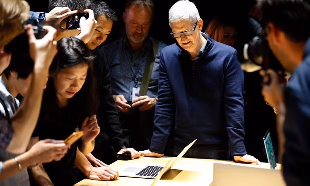 Tim Cook, CEO of Apple, looks on as guests inspect a new MacBook Pro. Photograph: Tony Avelar/EPA