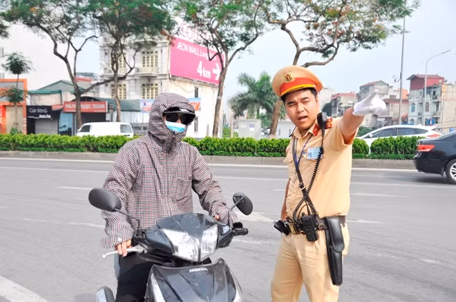 A traffic police officer working on Chuong Duong Bridge is directing vehicles in the hot weather.