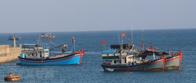 The national flag fluttes on the mast of Vietnamese fishing vessels anchored on Da Tay A island.