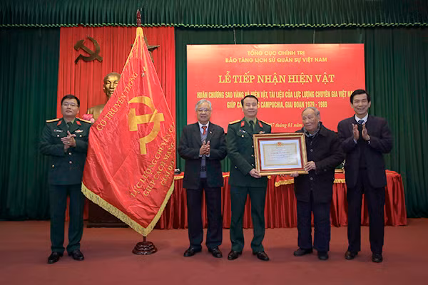 A representative of the Vietnam Museum of Military History receiving keepsakes of former Vietnamese experts who had worked in Cambodia.