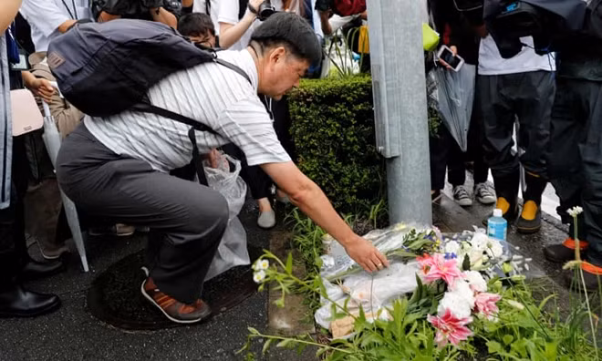 A man places flowers near the Kyoto Animation building to mourn the victims of the arson attack in Japan. Photograph: Kim Kyung-Hoon/Reuters.