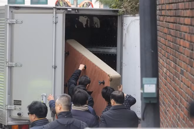 A bed was seen being loaded into the back of a lorry as workers removed dozens of bags and suitcases