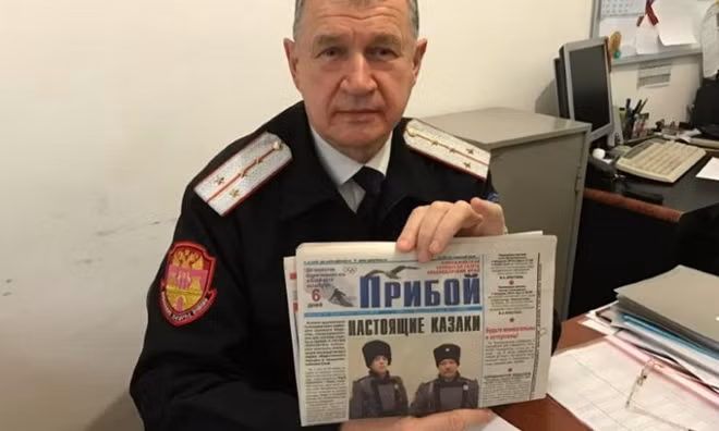 Russian Cossack commander Vladimir Bagliy shows a local newspaper with a picture of his fellow Cossack Yuri Sokalsky (R) killed near the Syrian city of Palmyra, in the Black Sea town of Gelendzhik, Russia, March 16, 2017. REUTERS/Maria Tsvetkova
