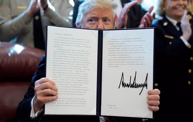 U.S. President Donald Trump holds up his veto of the congressional resolution to end his emergency declaration to get funds to build a border wall after signing it in the Oval Office of the White House in Washington, U.S., March 15, 2019. REUTERS