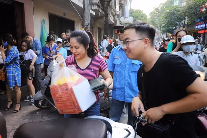 A woman is so happy after buying some traditional mid-autumn cakes from the shop.