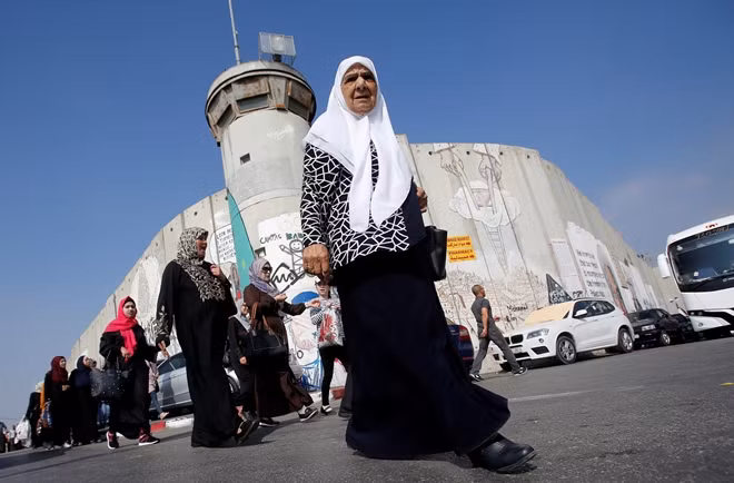 Palestinians pass by a section of the controversial Israeli barrier on their way to attend Friday prayer of the holy fasting month of Ramadan in Jerusalem's Al-Aqsa mosque, in Bethlehem in the occupied West Bank June 1, 2018. REUTERS