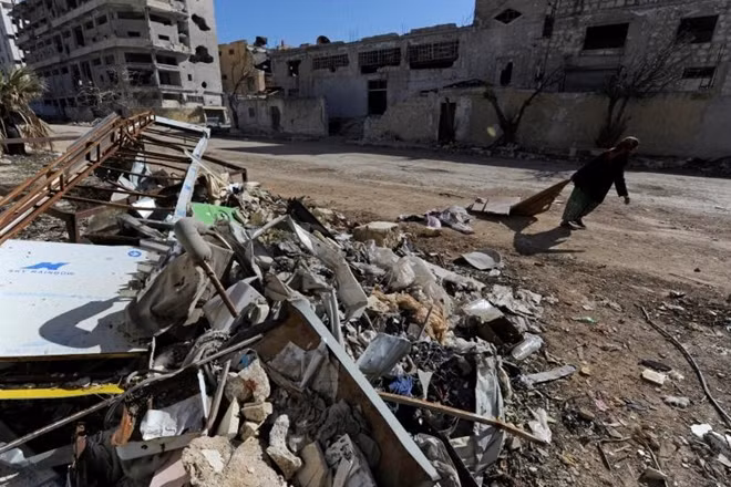 A woman walks past debris along a street in Aleppo's Belleramoun Industrial Zone, Syria February 2, 2017. Picture taken February 2, 2017. REUTERS