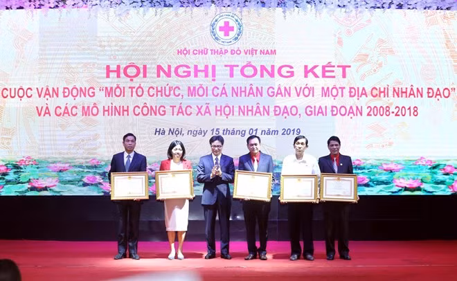 Deputy Prime Minister Vu Duc Dam (third, left) presents merit certificates to collectives and individuals with great contribution to humanitarian activities at the meeting on January 15 (Photo: VNA)