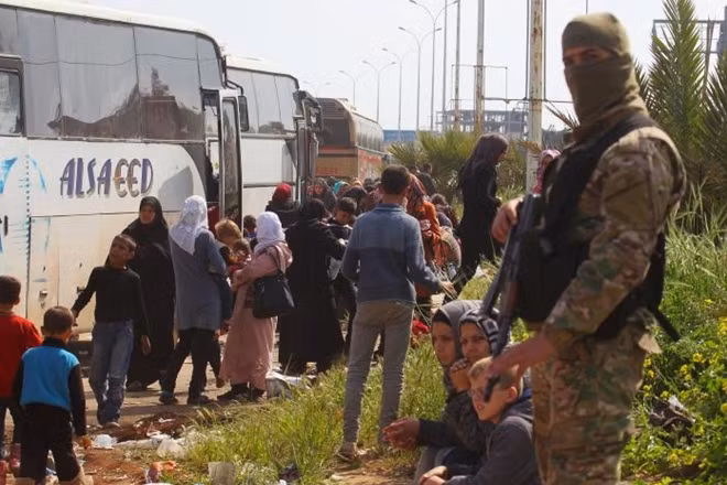 A rebel fighter stands near buses carrying people that were evacuated from the two villages of Kefraya and al-Foua, after a stall in an agreement between rebels and Syria's army, at insurgent-held al-Rashideen, Aleppo province, Syria April 15, 2017. REUTERS/Ammar Abdullah
