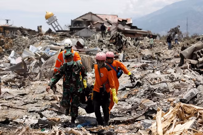 Rescue workers and a soldier remove a victim of last week's earthquake in the Balaroa neighbourhood in Palu, Central Sulawesi, Indonesia October 6, 2018. REUTERS/Darren Whiteside