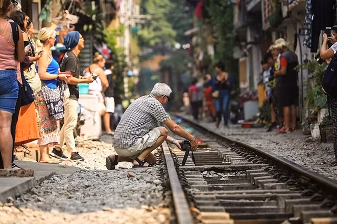 A foreigner is setting up his camera to capture some shots at the train street