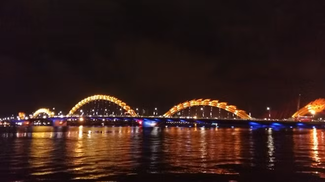 Dragon Bridge spans a colourful light at night in the Han River in Da Nang.