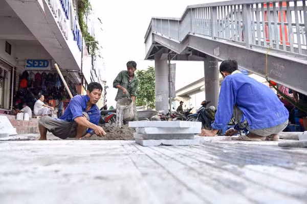 Workers lay out stone tiles on the pavement of Nguyen Trai Street, Thanh Xuan District, Ha Noi