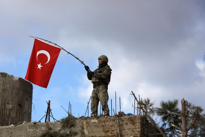 A Turkish soldier waves a flag on Mount Barsaya, northeast of Afrin, Syria January 28 ,2018. REUTERS