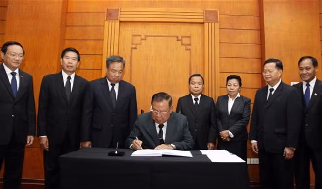 LPRP General Secretary and President of Laos Bounnhang Volachith writes in the condolence book for former Party General Secretary Do Muoi. (Photo: VNA)