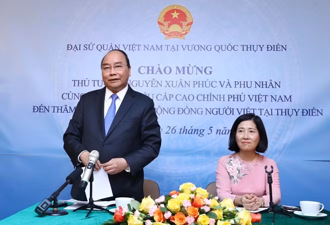 Prime Minister Nguyen Xuan Phuc (standing) speaks at the meeting with the Vietnamese Embassy staff and expatriates in Sweden.