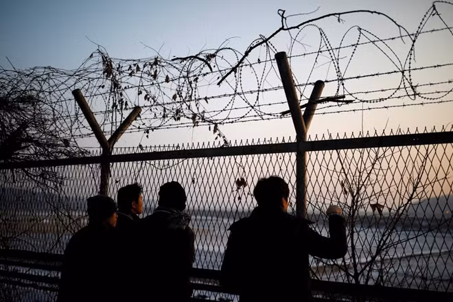 People look toward the north through a barbed-wire fence near the militarized zone separating the two Koreas, in Paju, South Korea, December 21, 2017. REUTERS/Kim Hong-Ji