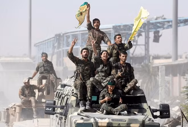 Syrian Democratic Forces (SDF) fighters ride atop military vehicles as they celebrate victory in Raqqa, Syria, October 17, 2017. REUTERS/Erik De Castro