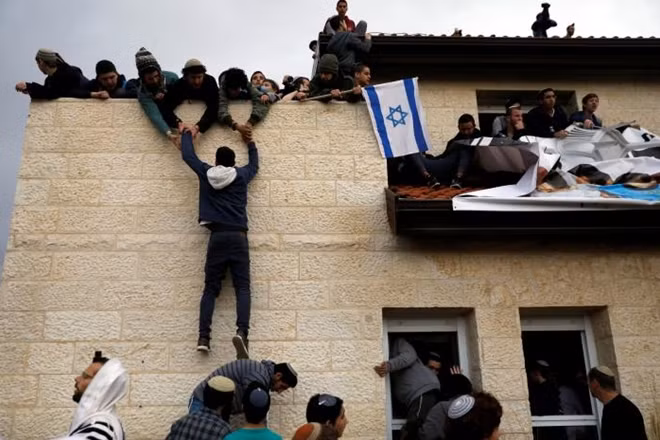 A pro-settlement activist climbs onto a rooftop of a house to resist evacuation of some houses in the settlement of Ofra in the occupied West Bank, during an operation by Israeli forces to evict the houses. REUTERS/Ronen Zvulun