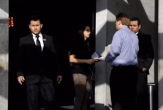 A security employee (L) looks on as a recruiter from Tesla (C) talks to a job seeker at the hotel where the electric vehicle maker is holding a recruiting event for its California factory, in the municipality of San Pedro Garza, neighbouring Monterrey, May 5, 2017. REUTERS/Daniel Becerril