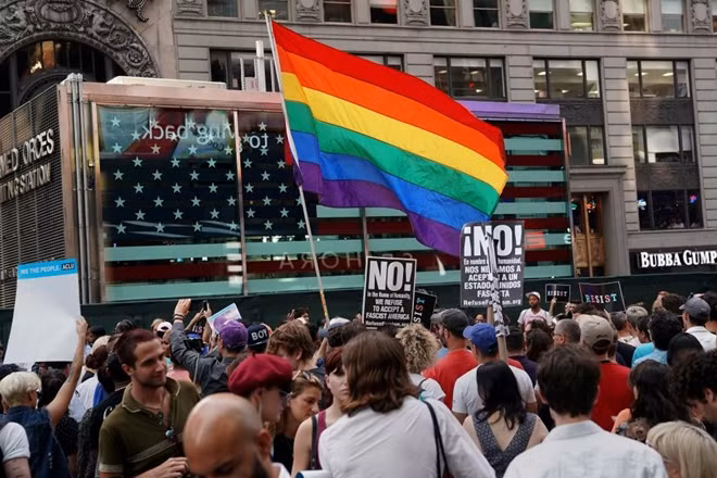 A rainbow flag flies as people protest U.S. President Donald Trump's announcement that he plans to reinstate a ban on transgender individuals from serving in any capacity in the U.S. military, in Times Square, in New York City, New York, U.S., July 26, 2017. REUTERS/Carlo Allegri/File Photo
