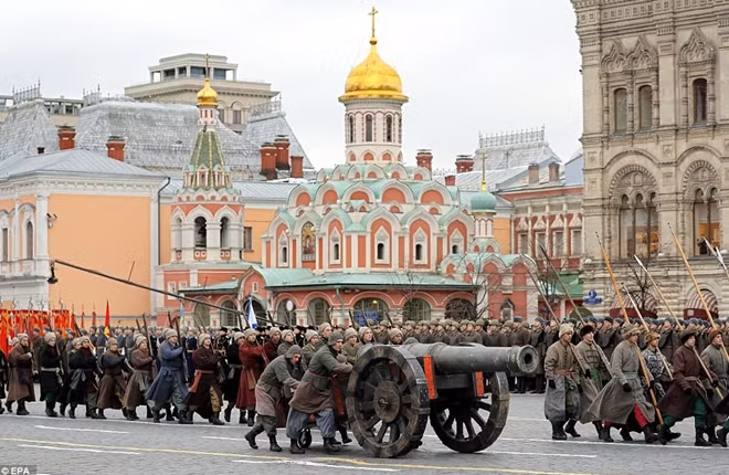 Russian performers push a huge, old cannon down through the streets of Moscow alongside others carrying huge spears.