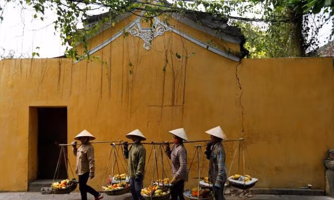 Women wearing traditional hats, known as non la, sell fruits in Hoi An, Vietnam. Photo by Reuters