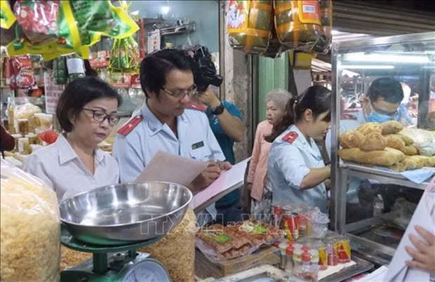 Officers of HCM City's food safety management board inspect invoices of a store in a traditional market in District 4. (Photo: VNA)