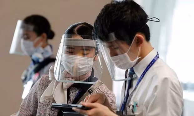Staff members of Japan's All Nippon Airways wearing protective masks and face shields work at a boarding gate at Haneda Airport in Tokyo on June 4, 2020. (Photo: Reuters)