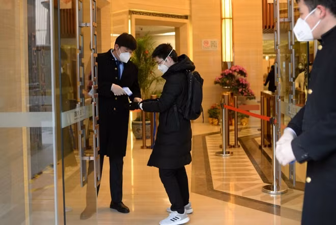 Jin Yang, 28, who works in a department of China's State Administration of Foreign Exchange, receives temperature check at an entrance to his company, in the morning on his first day of returning to work after the extended Lunar New Year holiday caused by the novel coronavirus outbreak, in Beijing, China February 10, 2020. REUTERS/Tingshu Wang