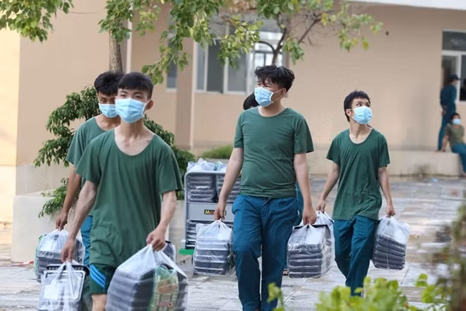 Military personnel delivering meals to patients at treatment area.